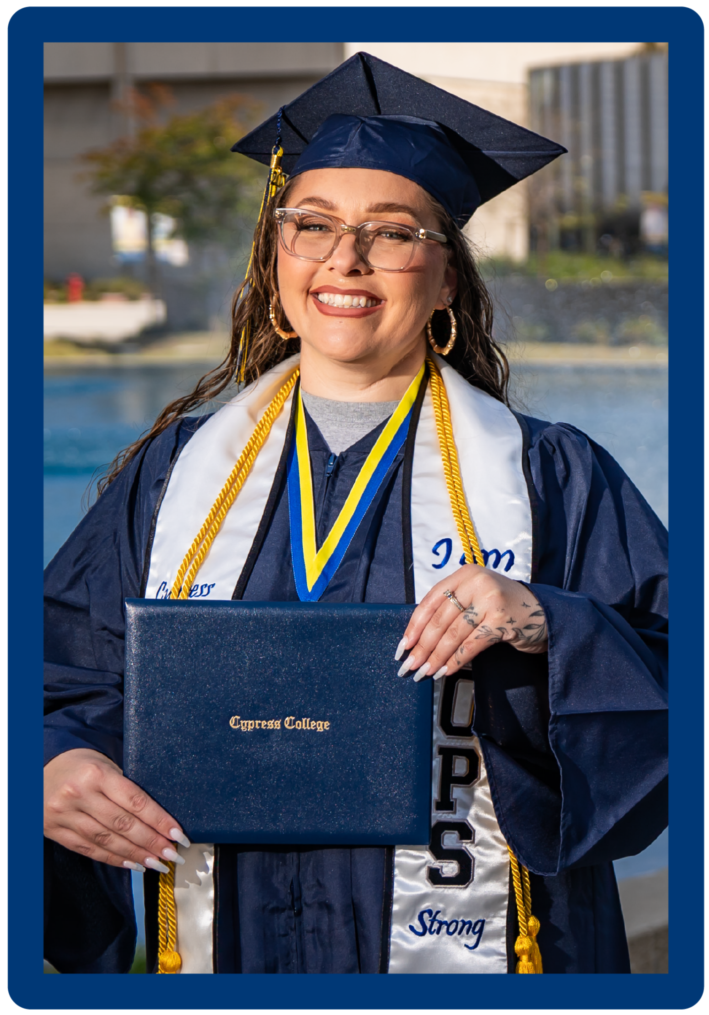 portrait of 2024 Outstanding Graduate of the Year, Ashleigh Carter, wearing her graduation regalia, including an EOPS sash, gold honor cords signifying high honors, and holding a Cypress College diploma cover