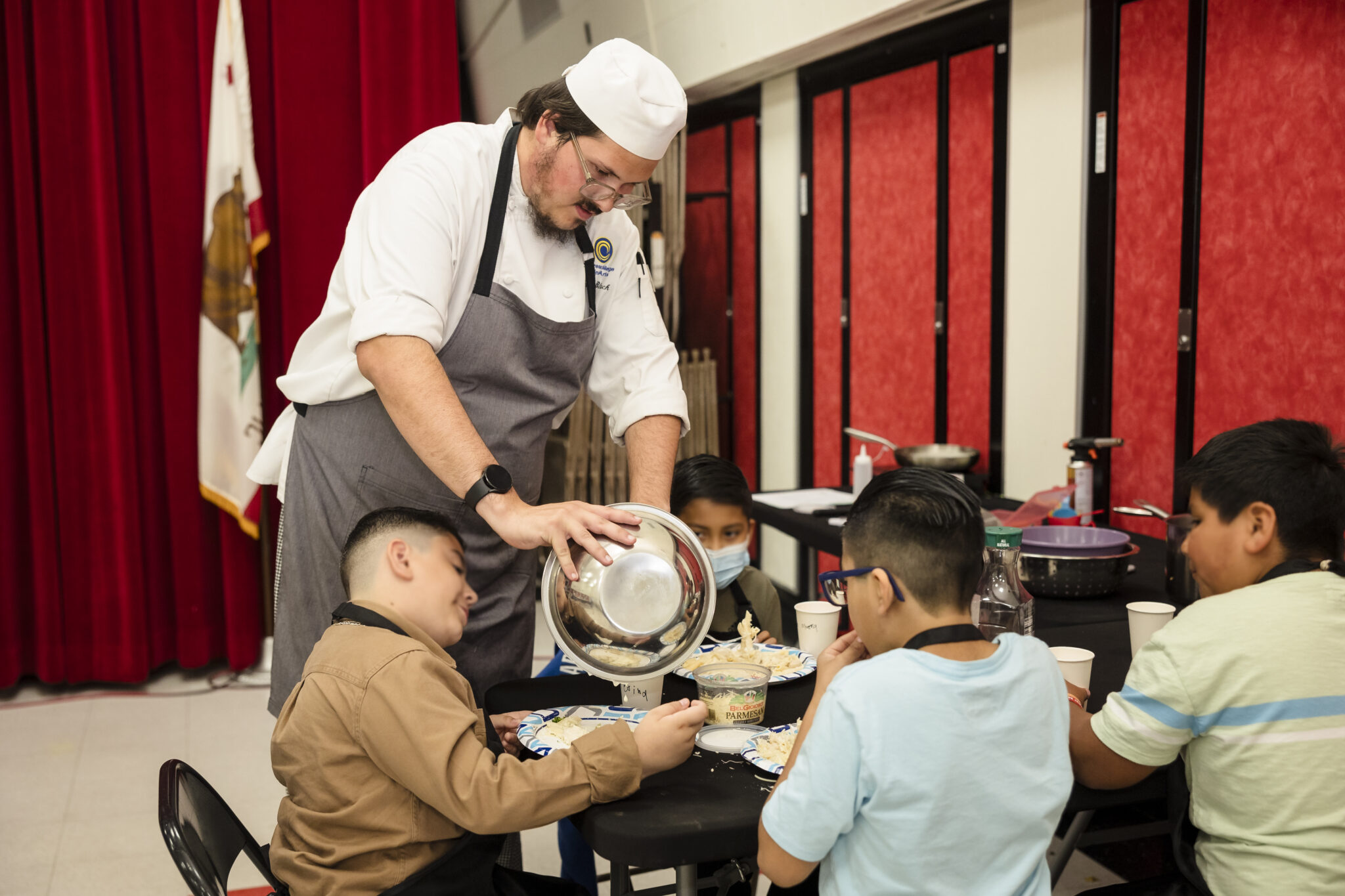 A Cypress College student serves food to elementary school students. 