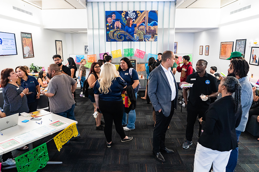 Students and college employees gather in a room to mingle and eat popsicles